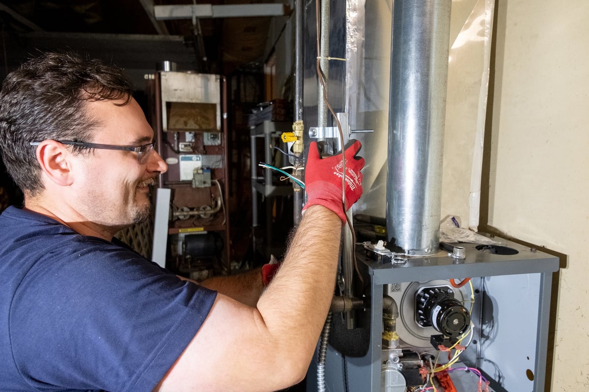 Technician in red gloves working on HVAC system components indoors